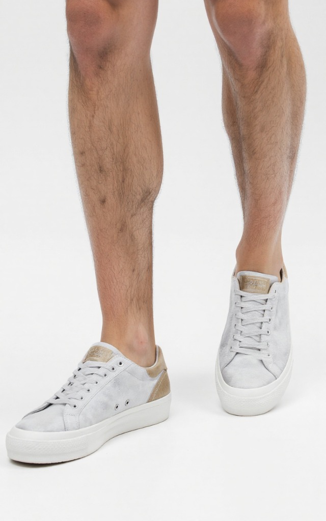 A male model wearing Sneakers with low   tops, against a white background, with a close   up of the feet